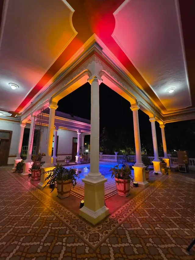 Patio central iluminado de noche con luces rosas y doradas durante un evento