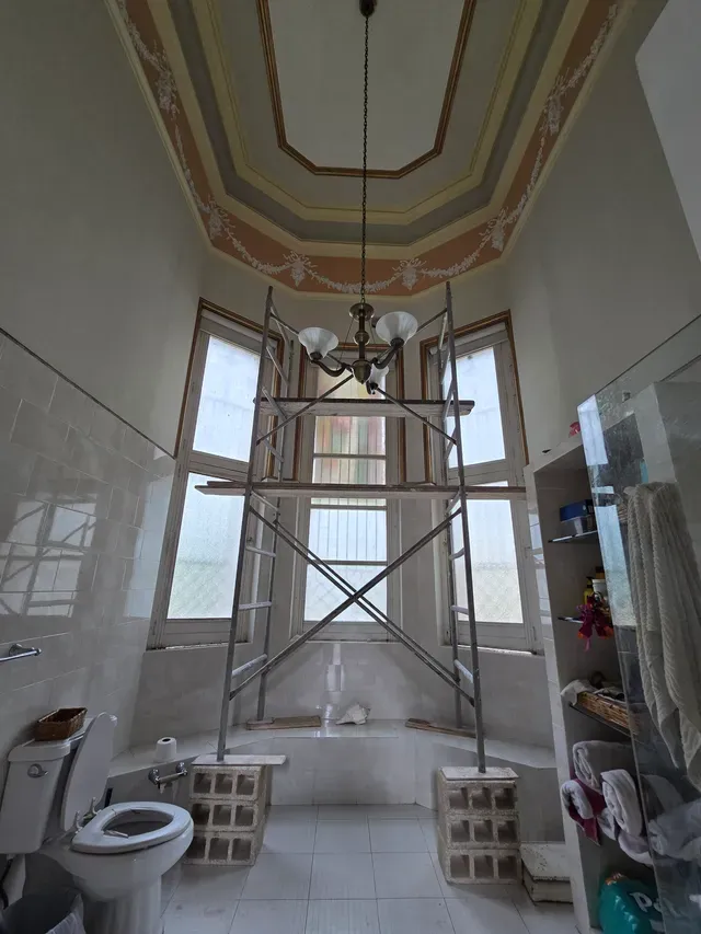 Baño en renovación, con andamio interior y el techo pintado original de fondo